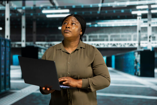 Admin working with notebook computer to do maintenance in server facility with setup helping companies stay connected.