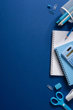 Back to school vertical stylish flat lay with blue stationery, notebooks, calculator and study supplies on deep blue backdrop