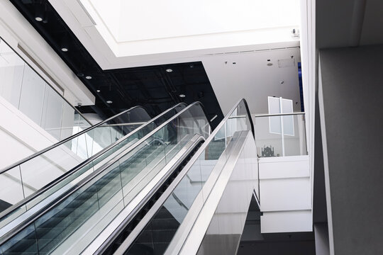 Modern empty shopping mall interior with escalators and contemporary architecture. Quiet retail space without customers. Commercial property. Consumer economy and urban lifestyle..