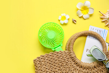 Naklejka premium Bag with female summer accessories, passport, ticket and mini fan on yellow background with space for text