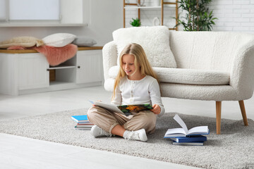 Obraz premium Little girl reading book on floor at home