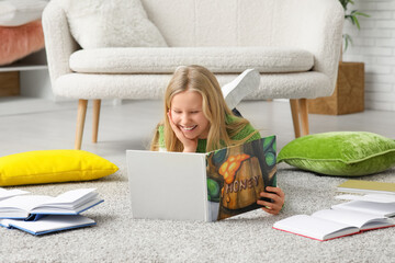 Obraz premium Happy little girl reading book on floor at home