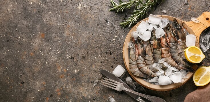 Fresh raw shrimp on ice with lemon and rosemary