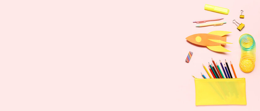 Colorful school supplies with paper rocket on pink background