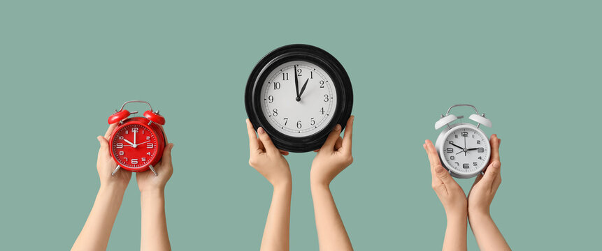 Hands holding different alarm clocks showing various times