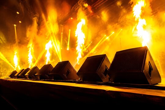 Row Of Wedge Stage Monitors Lining Stage Edge Under Intense Yellow And Orange Pyrotechnic Fire