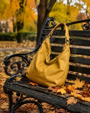 Mustard Yellow Hobo Handbag Slouched On A Wrought Iron Park Bench Surrounded By Autumn Leaves