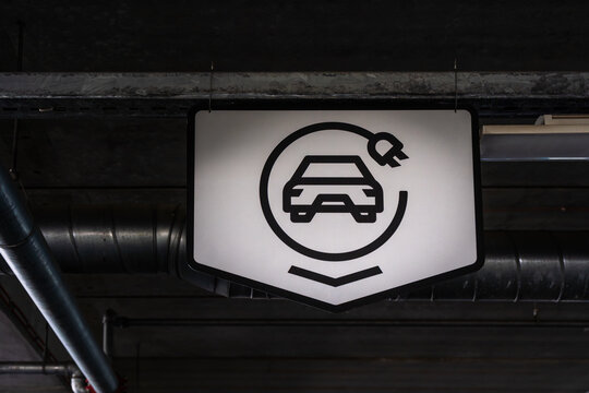 Electric vehicle charging sign in dark parking garage for sustainable urban mobility