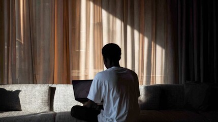 Fototapeta premium Back view of man working on laptop by window.