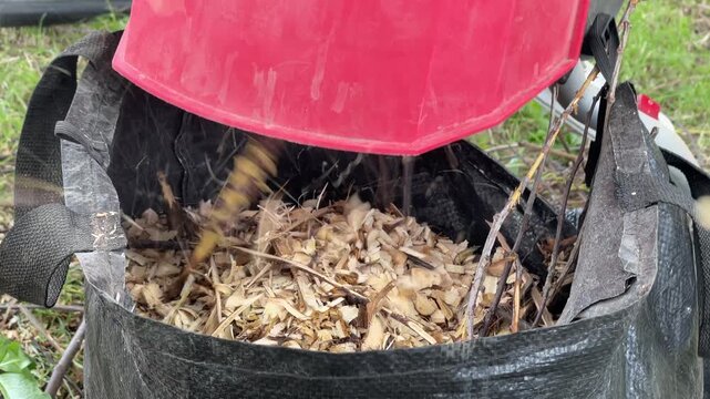 Garden shredder filling a bag with fresh wood chips