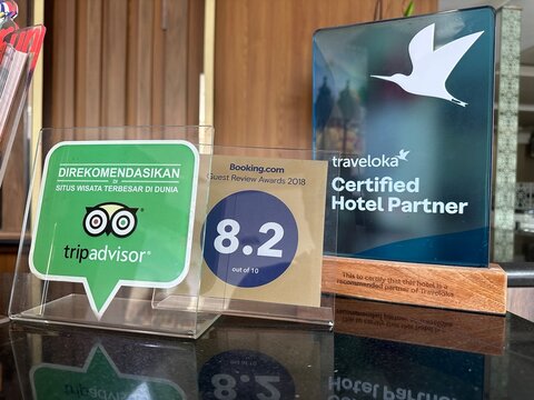 Yogyakarta, Indonesia July 7 2026 : Traveler Seals TripAdvisor and Traveloka Award Signs on Hotel Reception Desk