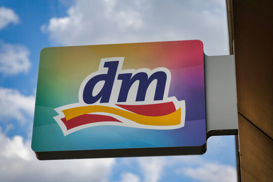 Cologne, Germany July 04 2026: The official logo of dm-drogerie markt on a storefront sign with a modern, colorful gradient under a blue sky. Symbol for retail and commerce.