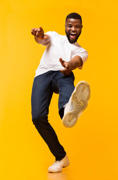 Gotcha. Emotional african american guy pointing fingers at camera over orange studio background, low angle view