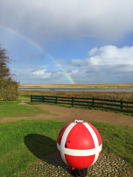 Rainbow over an Old Sea Mine now painted as a charity box for collecting money near the beach, Sonderho, Fanoe, Jutland, Denmark
