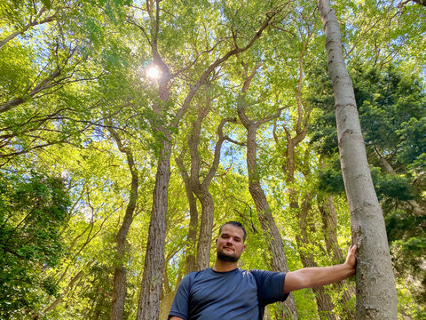 Male hiker standing in a forest leaning against a tree, Ferguson Canyon, Utah, USA