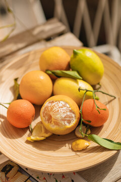 Close-up of Fresh oranges, tangerines and lemons in a wooden bowl on a sunny balcony