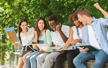 Exam Results. Group Of Joyful International Students Celebrating Success With Laptop Outdoors, Checking Their Test Scores Online