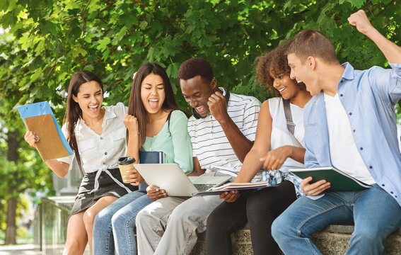 Exam Results. Group Of Joyful International Students Celebrating Success With Laptop Outdoors, Checking Their Test Scores Online
