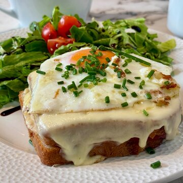 Close-up of a croque madame toasted sandwich with a side salad
