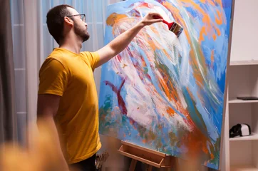 Fototapete Gemälde Man creating large canvas masterpiece in a studio workspace where brushwork, oil paint and canvas details show an active artistic workflow.  © DC Studio