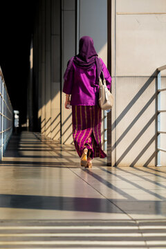 Rear view of a Woman wearing a purple hijab walking along a corridor