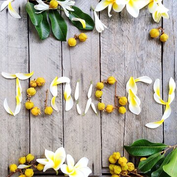 Overhead view of the word January spelled out in yellow flower petals and berries on a wooden table with floral decorations