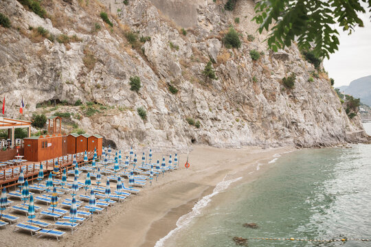Empty sun loungers and sun umbrellas on Spiaggia del Lannio beach at dawn, Cetara, Salerno, Italy