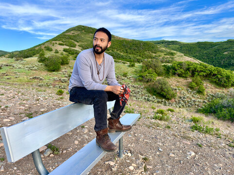 Hipster man Sitting on a Metal Bench at Sunset Point on the Wild Rose Loop Trail, North Salt Lake, Salt Lake City, Utah, USA