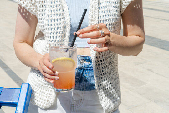 Close-up of a Woman standing at an outdoor cafe on a summer day holding a refreshing grapefruit lemonade drink