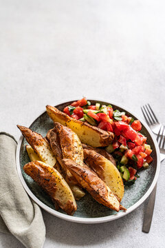 Close-up of a plate of Baked potato wedges with pico de Gallo on a table