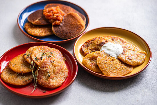 Close-up of three different coloured plates with Potato pancakes (draniki) and various sauces