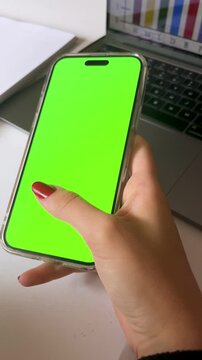 Vertical 4k video of a woman working with her cellphone. Professional smartphone mockup with green screen ready for advertising projects.