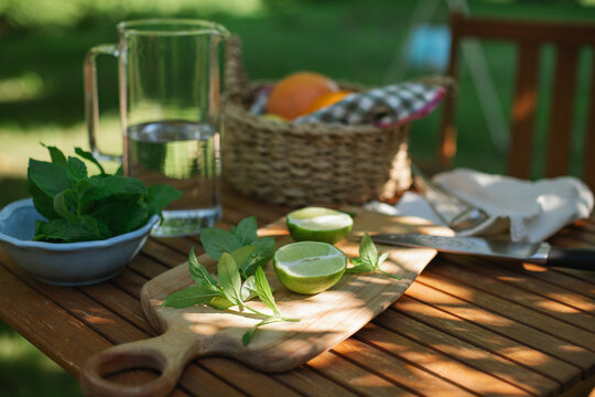 Pitcher of water, fresh lime and mint leaves on a garden table on a sunny summer day