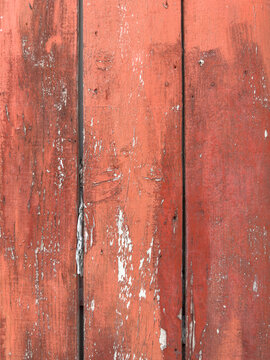 A vertical view of weathered red wooden planks showing distressed paint texture, perfect for rustic backgrounds or architectural design inspiration