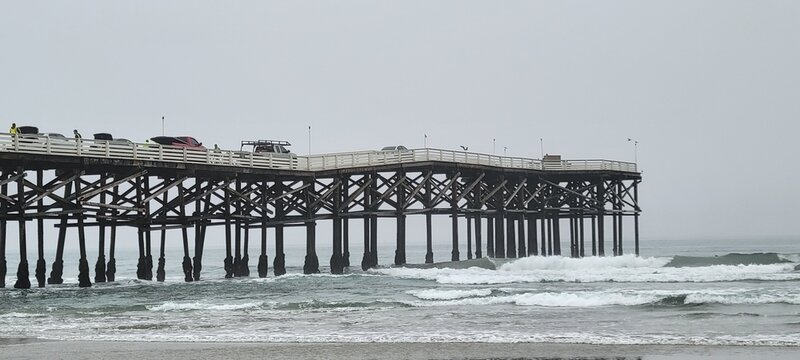 Detailed close up view of the wooden support pillars of Crystal Pier as ocean waves crash underneath at Pacific Beach, San Diego, California