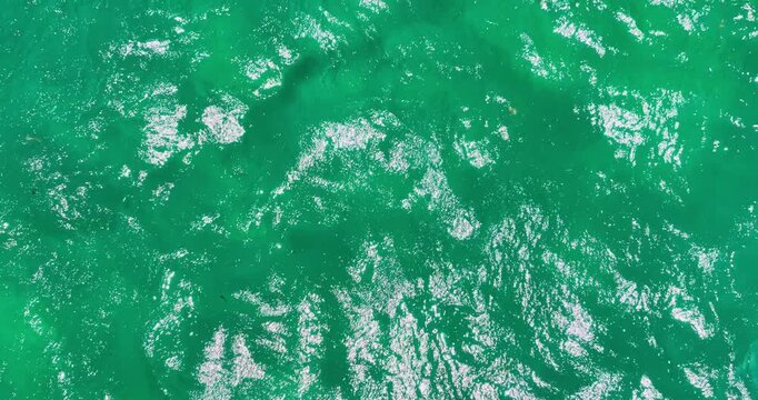 Aerial view of turquoise ocean sea water surface with white foam and ripples, ocean waves background