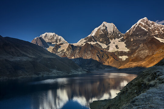 At the edge of Carhuacocha lagoon, the great triumvirate of the Cordillera Huayhuash reveals itself in a reflection of almost unbearable clarity. Siula Grande, Yerupaj&aacute; and Jirishanca rise in savage, 