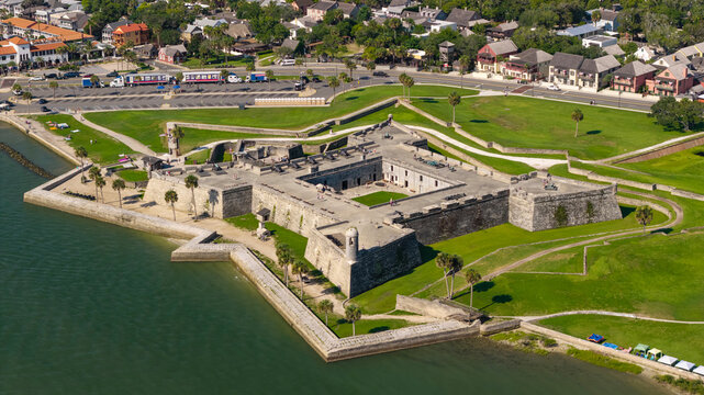 Aerial view of the Castillo de San Marcos in St. Augustine, FL. This 17th-century fort glows in the morning sunlight on July 4th, surrounded by lush lawns, palm trees, and the Matanzas River.