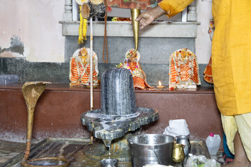Obraz premium Hindu Priest Performing Shiva Lingam Abhishek Ritual Inside Hindu Temple