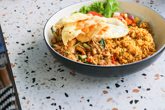 Authentic Indonesian Nasi Goreng served with a fried egg and crisp emping crackers in a bowl