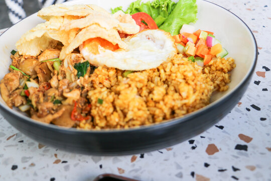 Savoring traditional Indonesian Nasi Goreng with crisp emping crackers on a terrazzo table