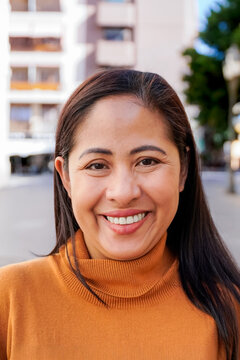 Mature asian woman smiling on camera with background city - Focus on face - Vertical photo