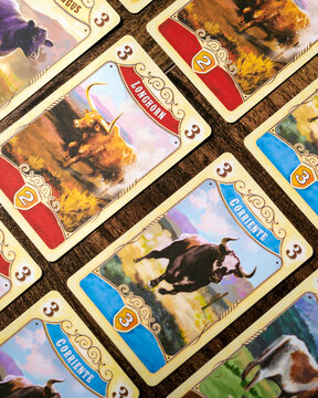 Portrait close up product photography of Great Western Trail game cards featuring diverse cattle livestock designs by Alexander Pfister and artist Chris Quilliams