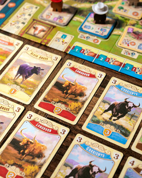 Portrait close up product photography of Great Western Trail game cards featuring diverse cattle livestock designs by Alexander Pfister and artist Chris Quilliams