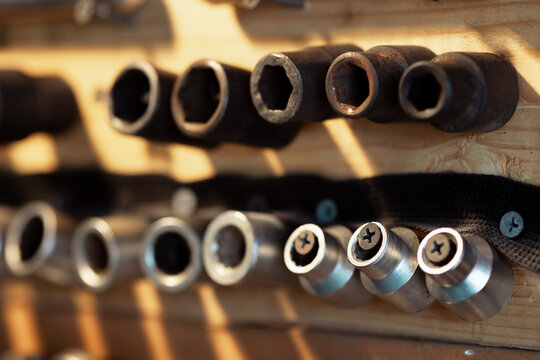 Wooden garage stand with tools for household appliance and transport belts. Traces of wear and dirt on the tools. Socket heads. Selective focus.