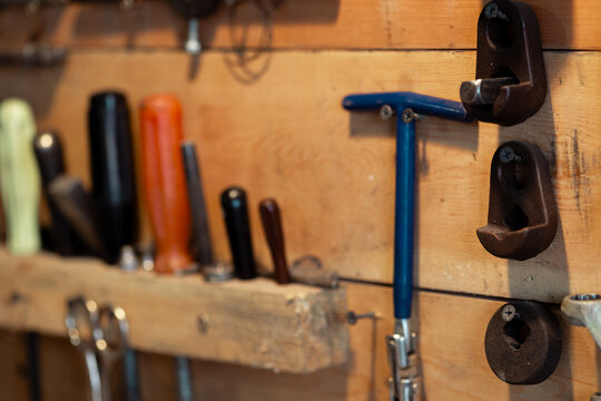 Wooden garage stand with tools for household appliance and transport belts. Traces of wear and dirt on the tools. Selective focus. Screwdrivers with plastic handles of different sizes. Thread cutting 
