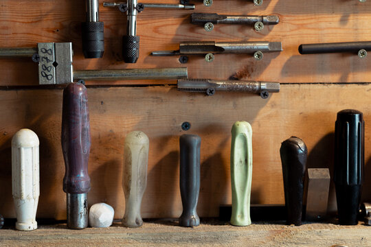 Wooden garage stand with tools for household appliance and transport belts. Traces of wear and dirt on the tools. Selective focus. Screwdrivers with plastic handles of different sizes. Thread cutting 