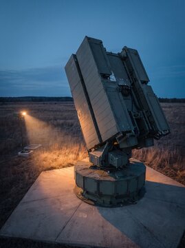 Advanced radar system or sensor array operating in a field at twilight, with a distant light source.