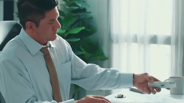 Professional engineer looking at phone while working on tablet with green screen at meeting table with turbine engine or jet engine sketch design and various metal gear scatter around. Alimentation.