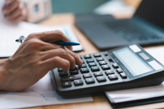 Accountant pressing calculator button for home evaluation report price. Male customer calculating real estate mortgage cost, house insurance premium or building loan